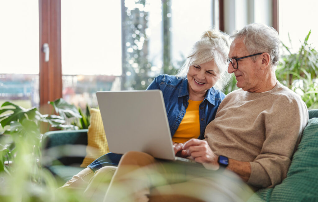 An older couple is looking at a laptop together.