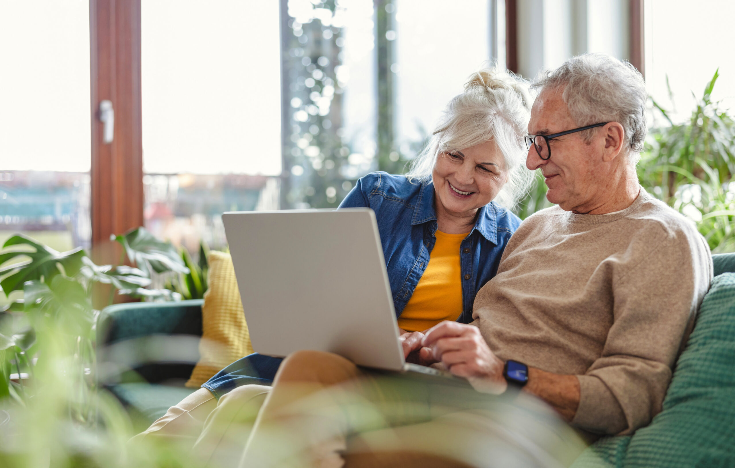 An older couple is looking at a laptop together.