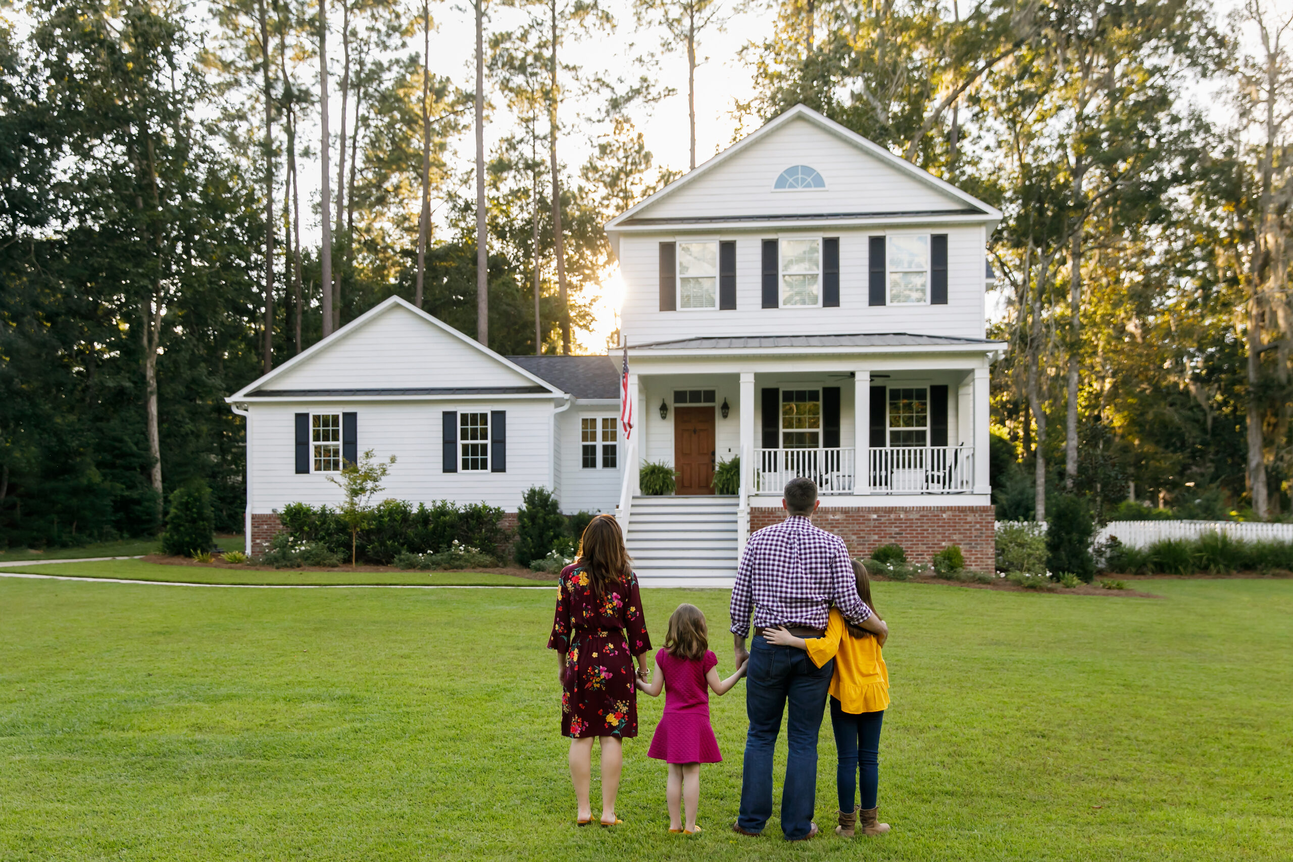 A family of four stands outside their home.