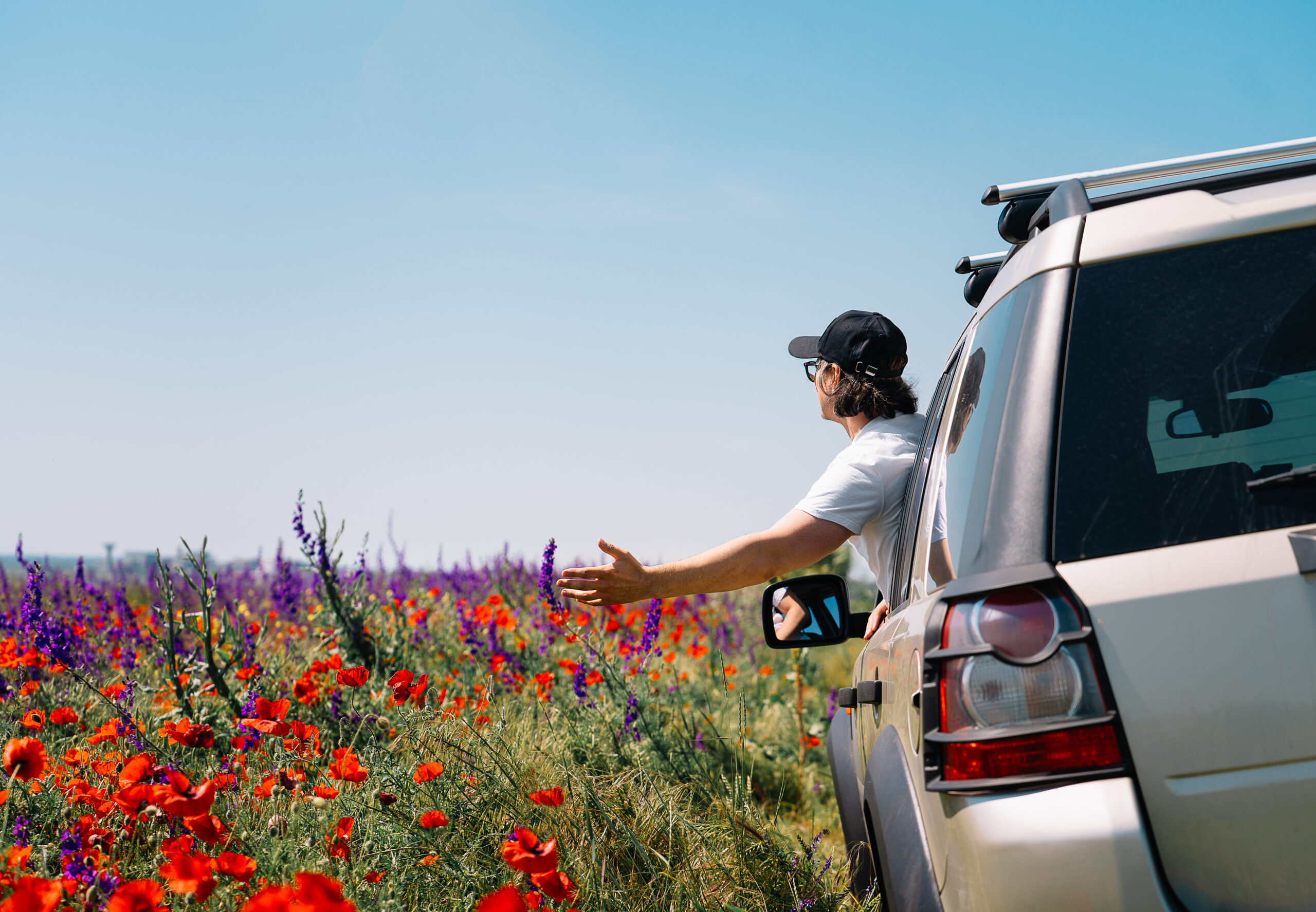 Person in a car by colorful meadow in spring.