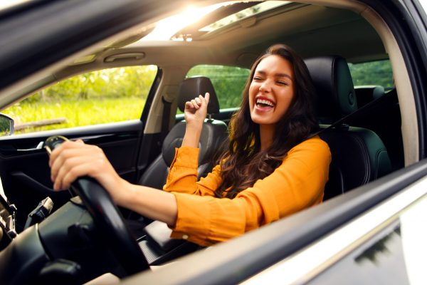 A woman happily driving her car.